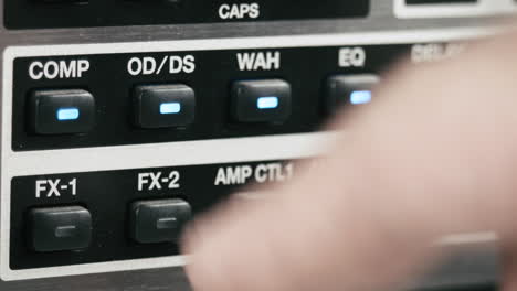 musician tests the parameters of a guitar preamp multi effect, macro shot