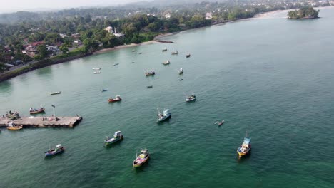 orbit shot of big number of fishermen boats with green landscape bay, weligama sri lanka