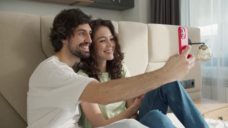 pareja alegre tomando un selfie con un teléfono inteligente en la habitación