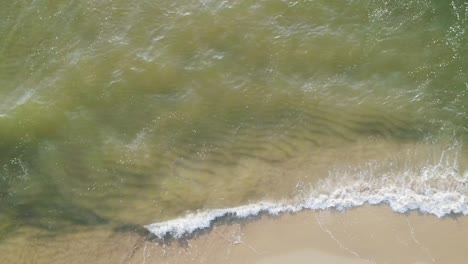 tropical beach aerial view, top view of waves break on tropical white sand beach. sea waves seamless loop on the beautiful sand beach.