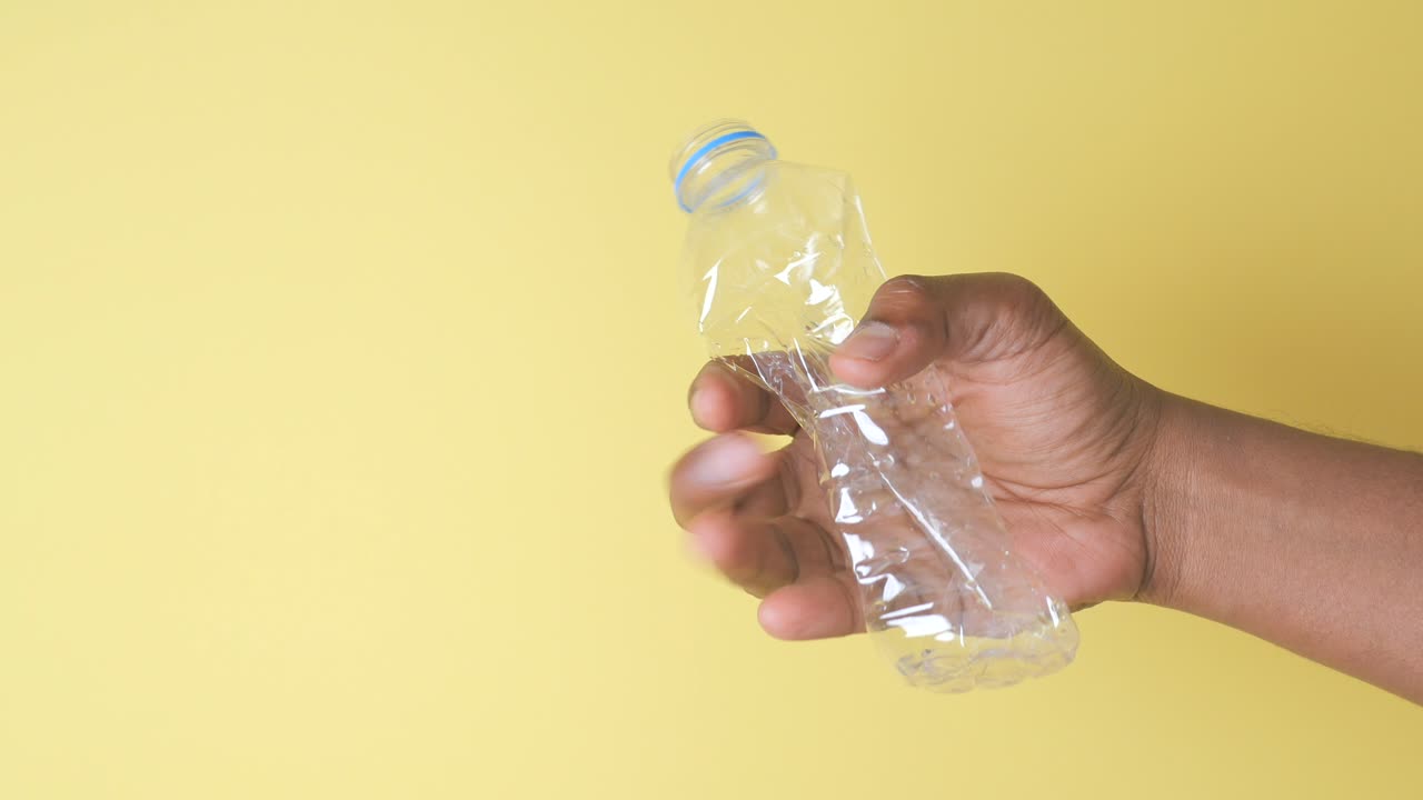 mano con una botella de agua de plástico triturada