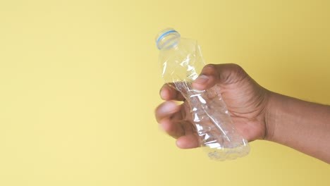 mano con una botella de agua de plástico triturada