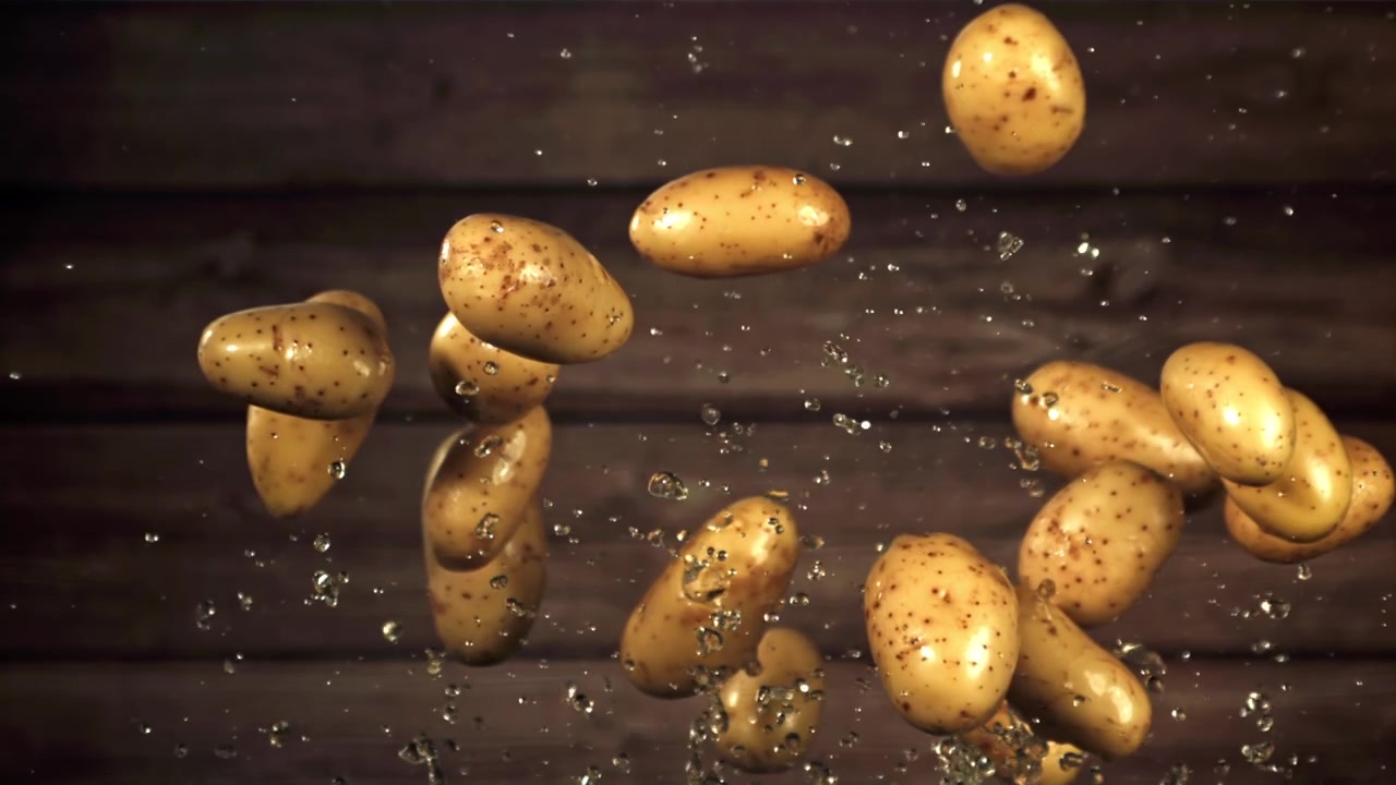 Patate fresche che cadono con schizzi d'acqua al rallentatore