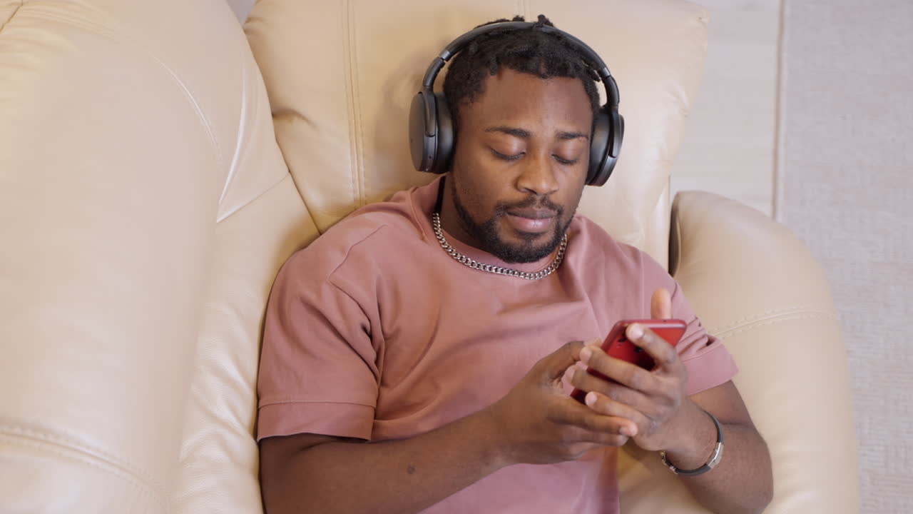 hombre relajándose en el sofá con auriculares y teléfono