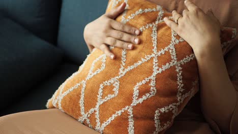 mujer sosteniendo una almohada de patrón naranja en un sofá