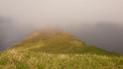 clouds float over the grassy peak of hornstrandir peninsula in iceland