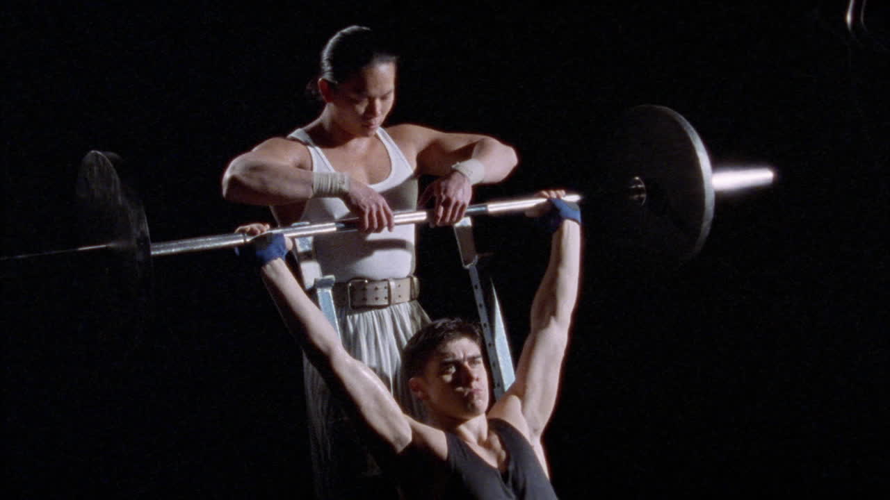 한 남자가 그를 돕는 다른 남자와 함께 바벨과 함께 일한다