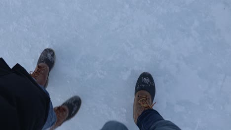couple with matching boots walking on frozen lake, point of view, slow motion
