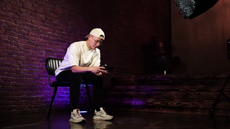 person sit and hold digital camera, moody indoor studio with lightning equipment