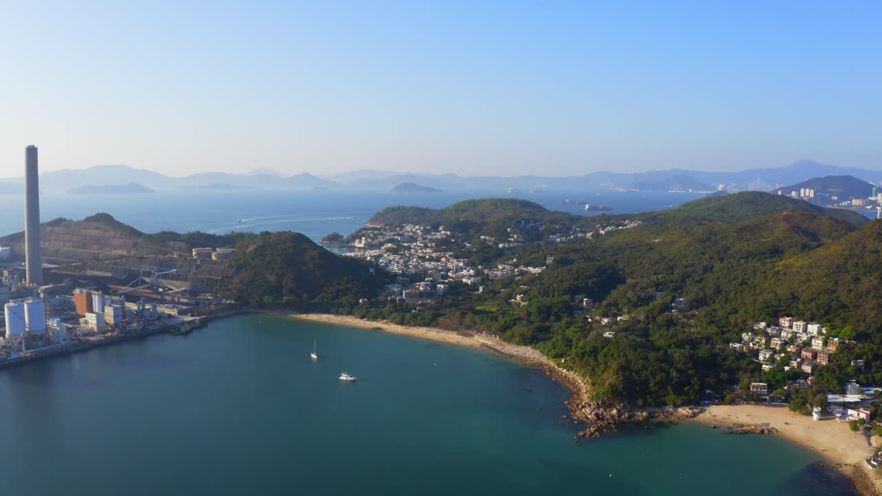 아름다운 화창한 날 해변이 있는 마을 옆 섬에 있는 큰 해안 석탄 화력 발전소의 드론 샷