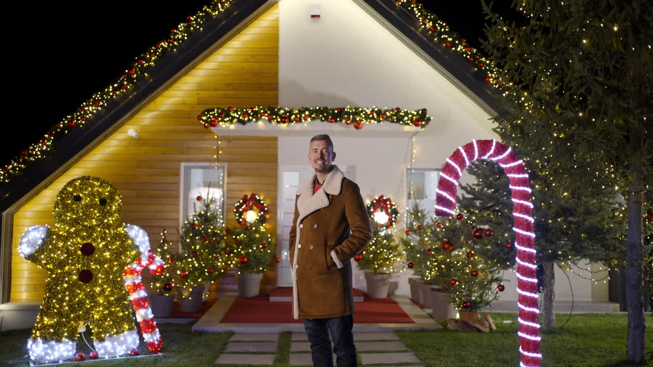 A man standing in front of a house decorated for Christmas