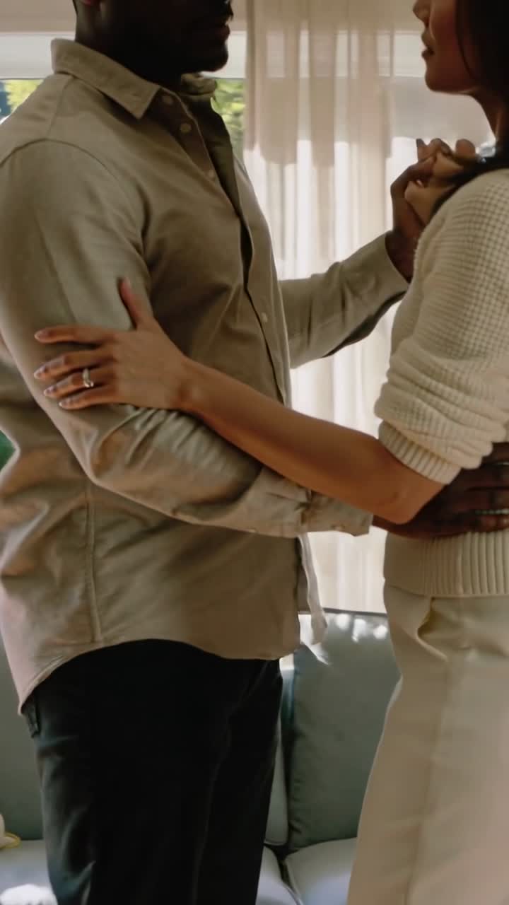 Casal em pé de frente, câmera recuando, segurando mãos com anéis, cortinas brilhando para casamento