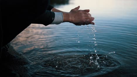 A-man-washing-hands-at-cold-nordic-lake-at-Sweden-during-sunset