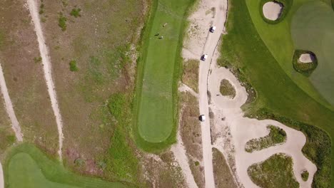 aerial birdseye view of links style golf course with players playing in southern california on a warm sunny day with lush fairways