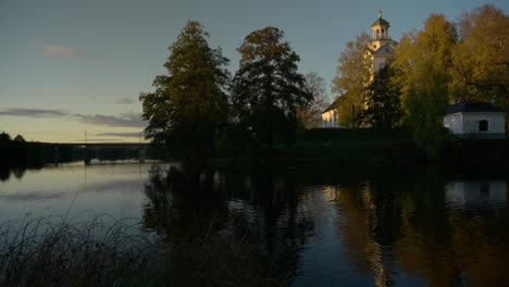 Eine-Weiße-Kirche-Mit-Reflexion-Im-Ruhigen-Wasser-Im-Abendlicht