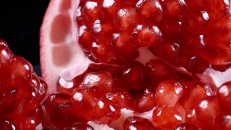 footage of rotating red pomegranate seeds on black background