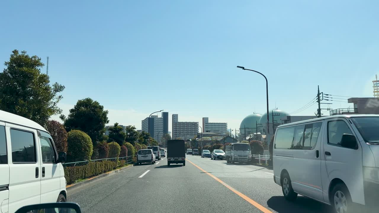 晴れた東京の道路を都市のスカイラインに向かって進む交通を捉えたドライブレコーダー。