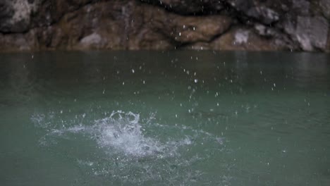 stone dropped into the lake, crystal clear water splash, rock hit still surface