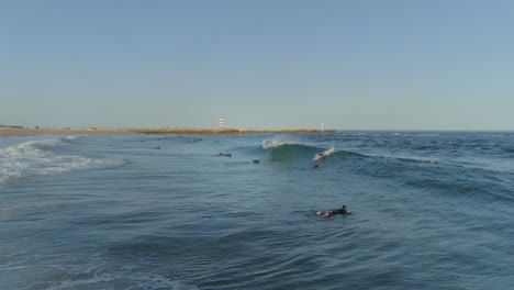 toma aérea de surfistas haciendo acrobacias de surf y disfruta montando las olas en un día soleado, algarve.