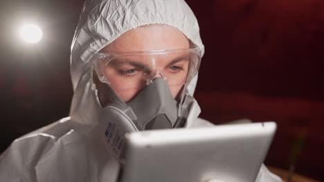 hombre con traje protector y máscara viendo un video de noticias sobre la epidemia en una tableta