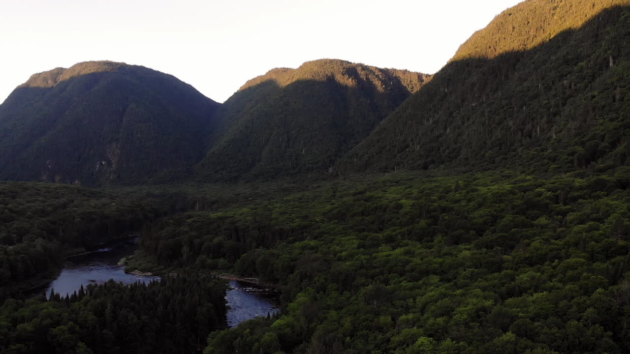 dron disparó sobre un valle y un río, 3 montañas al fondo