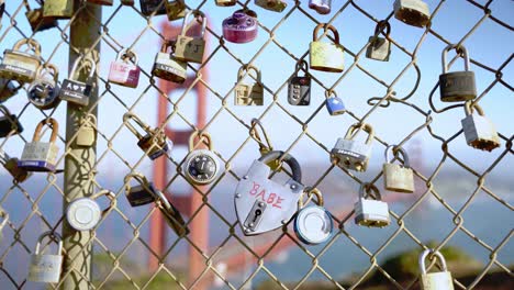 many locks on a wire metal fence and the golden gate bridge in the background