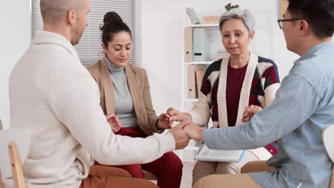 people holding hands sitting in circle