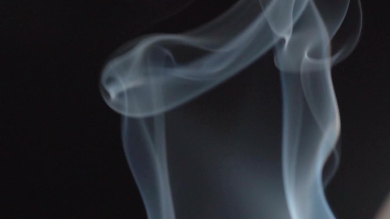 Fumo bianco astratto di incenso che si avvolge su uno sfondo scuro, creando motivi fluidi, curve morbide e movimento atmosferico in primo piano
