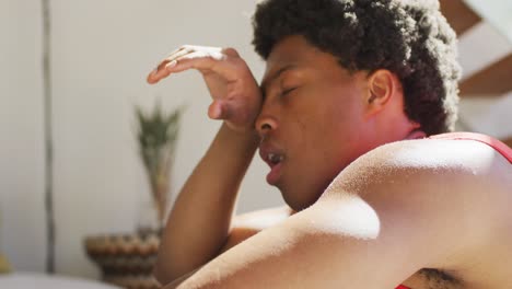 hombre afroamericano en forma haciendo ejercicio en casa y descansando cansado en casa