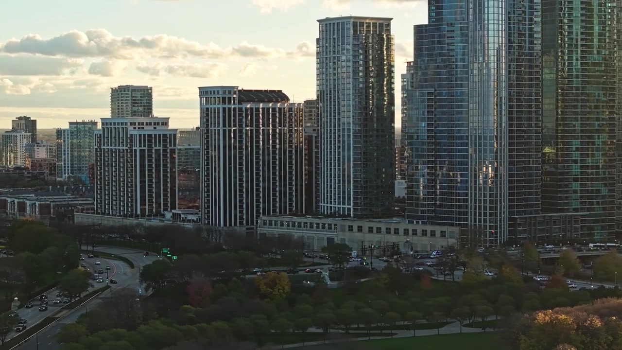 Vista aérea de um parque no centro de Chicago com arranha-céus iluminados, a histórica orla do rio e reflexos da hora dourada.