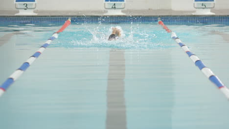 swimmer performing butterfly stroke in swimming pool, focusing on technique, copy space