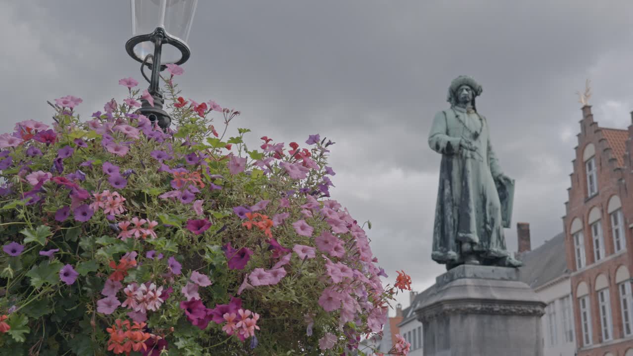 A low-angle view of the Statue of Jan van Eyck in Jan van Eyckplein (Jan van Eyck Square), a historic square in Bruges, Belgium