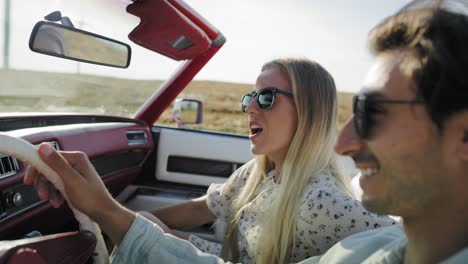 Close-up-video-of-smiling-couple-driving-in-a-cabriolet