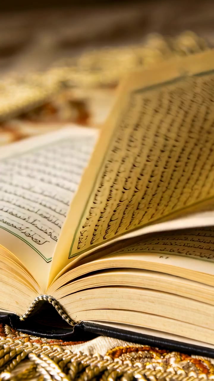 Video verticale: Corrente d'aria che solleva le pagine di un libro arabo rilegato su un tappeto da preghiera, mostrando il dorso cucito e il testo.