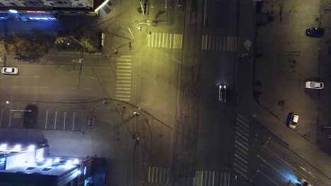 nighttime aerial view of city intersection with cars and pedestrians