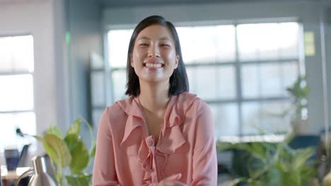 Portrait-of-happy-smart-casual-asian-businesswoman-at-office,-smiling-in-slow-motion