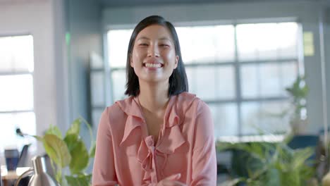 portrait of happy smart casual asian businesswoman at office, smiling in slow motion