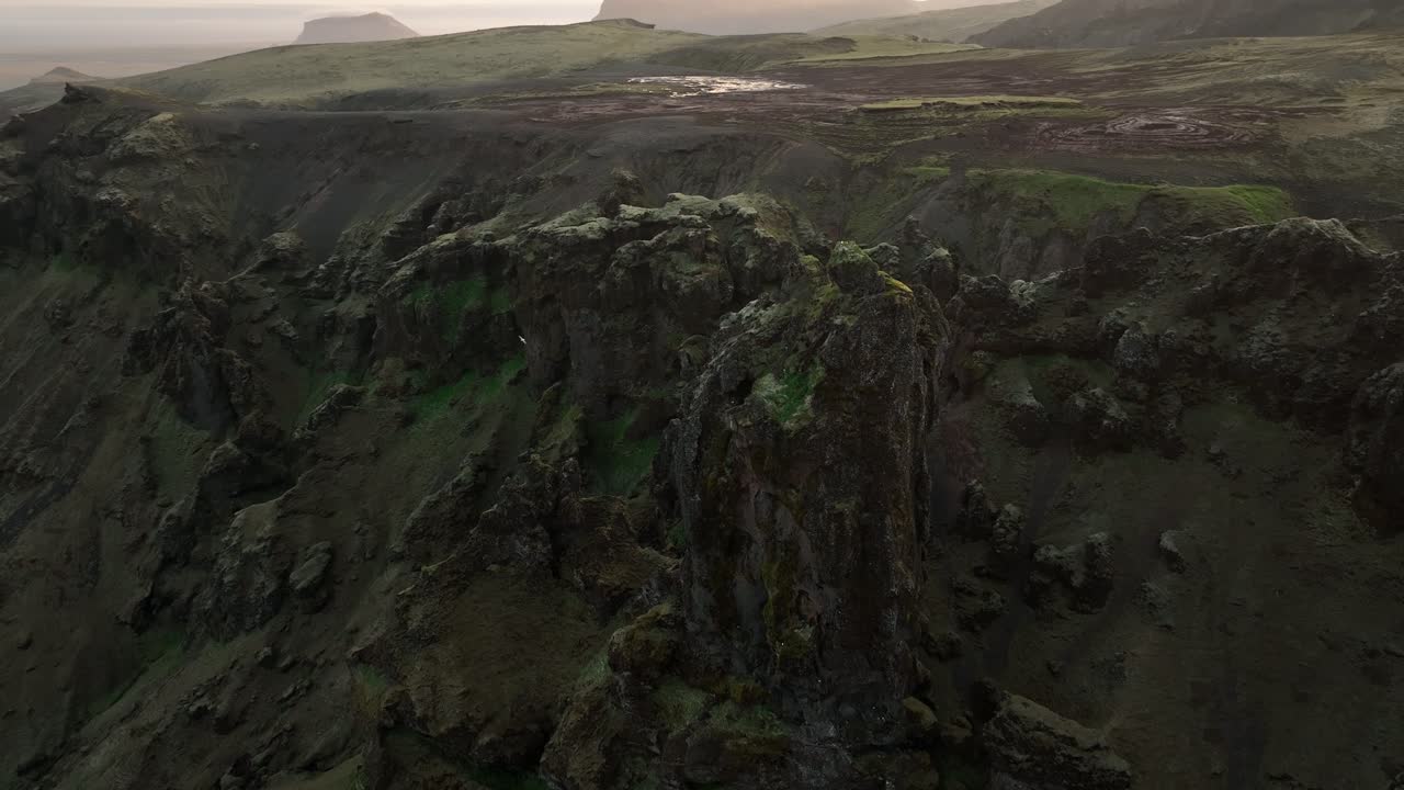 Aerial view of dramatic rocky cliffs and rugged volcanic terrain in North Iceland, showcasing jagged formations and expansive plains in the distance.