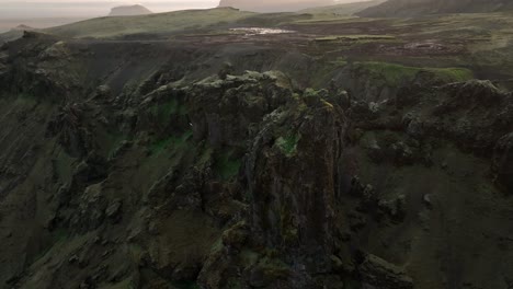 aerial view of dramatic rocky cliffs and rugged volcanic terrain in north iceland, showcasing jagged formations and expansive plains in the distance.
