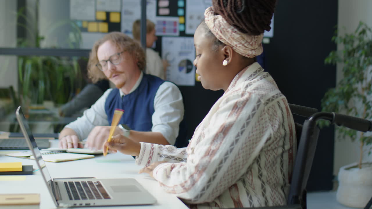 Woman in Wheelchair Working with Colleague in Office