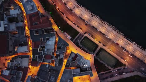 Cinematic-topdown-drone-shot-at-night-at-Bari,-Italy-with-cars-passing-on-the-road