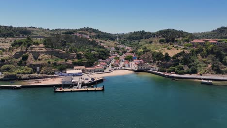 Drone-shot-of-the-ferry-point-and-the-tiny-beach-at-Porto-Brandao,-Portugal