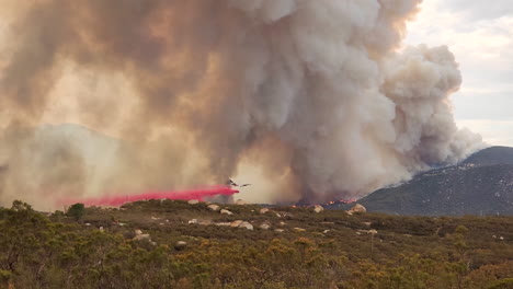 Imágenes-De-Incendios-Forestales-Y-Humo-Ondulante-Mientras-El-Avión-Vuela-Bajo-Para-Hacer-Una-Caída-De-Lodo-En-El-Furioso-Incendio-De-Fairview-En-Hemet,-California