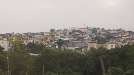 POV-Aufnahme-Aus-Dem-Auto-Auf-Der-Straße,-Die-Den-Favela-Slum-Von-Sao-Paulo-Auf-Einem-Hügel-An-Einem-Bewölkten-Tag-In-Brasilien-Zeigt