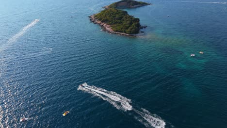 a speedboat races across the clear blue waters of ksamil, albania, with swimmers in the distance