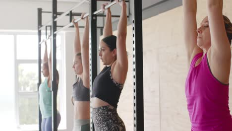 Unaltered-diverse-women-group-training-at-gym-doing-hanging-crunches-from-bars,-in-slow-motion