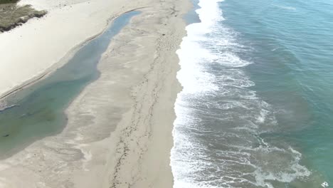 Forward-moving-up-tilt-of-empty-beach-revealing-amazing-rocky-cliffs-of-the-Pacific-Ocean-and-Highway-1-passing-on-the-left-hand-side-in-California,USA