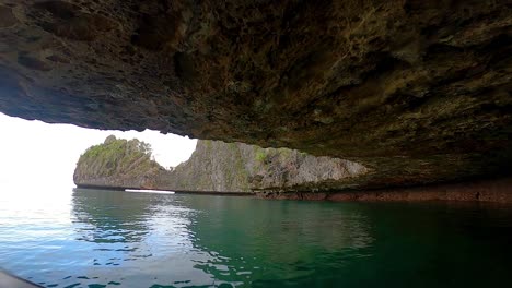 driving under a limestone island with a small boat