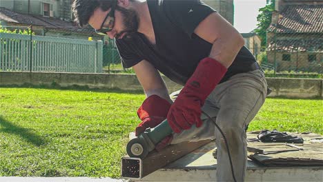 worker angle grinder cuts iron profile