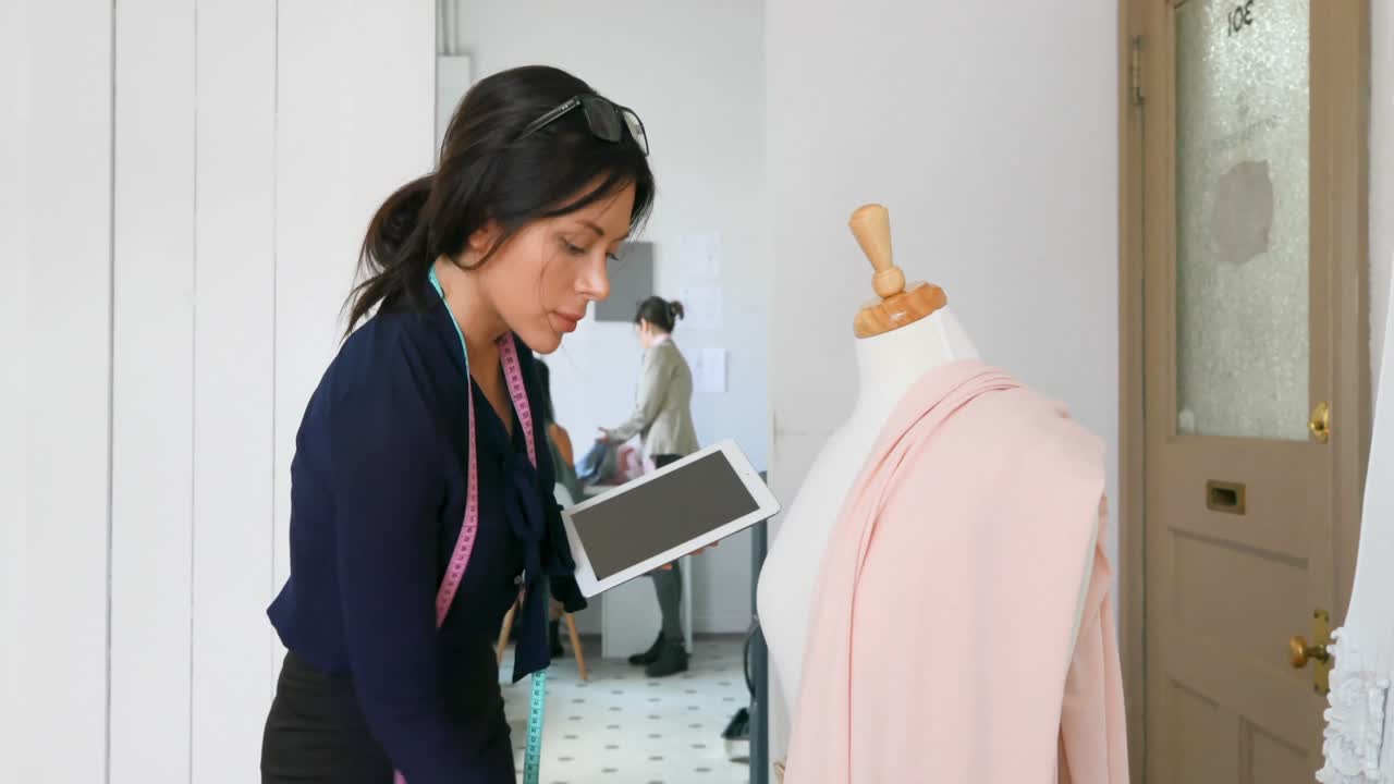 패션 디자이너가 드레스 메이커 모델 4k의 직물에서 작업하는 동안 태블릿을 사용합니다.